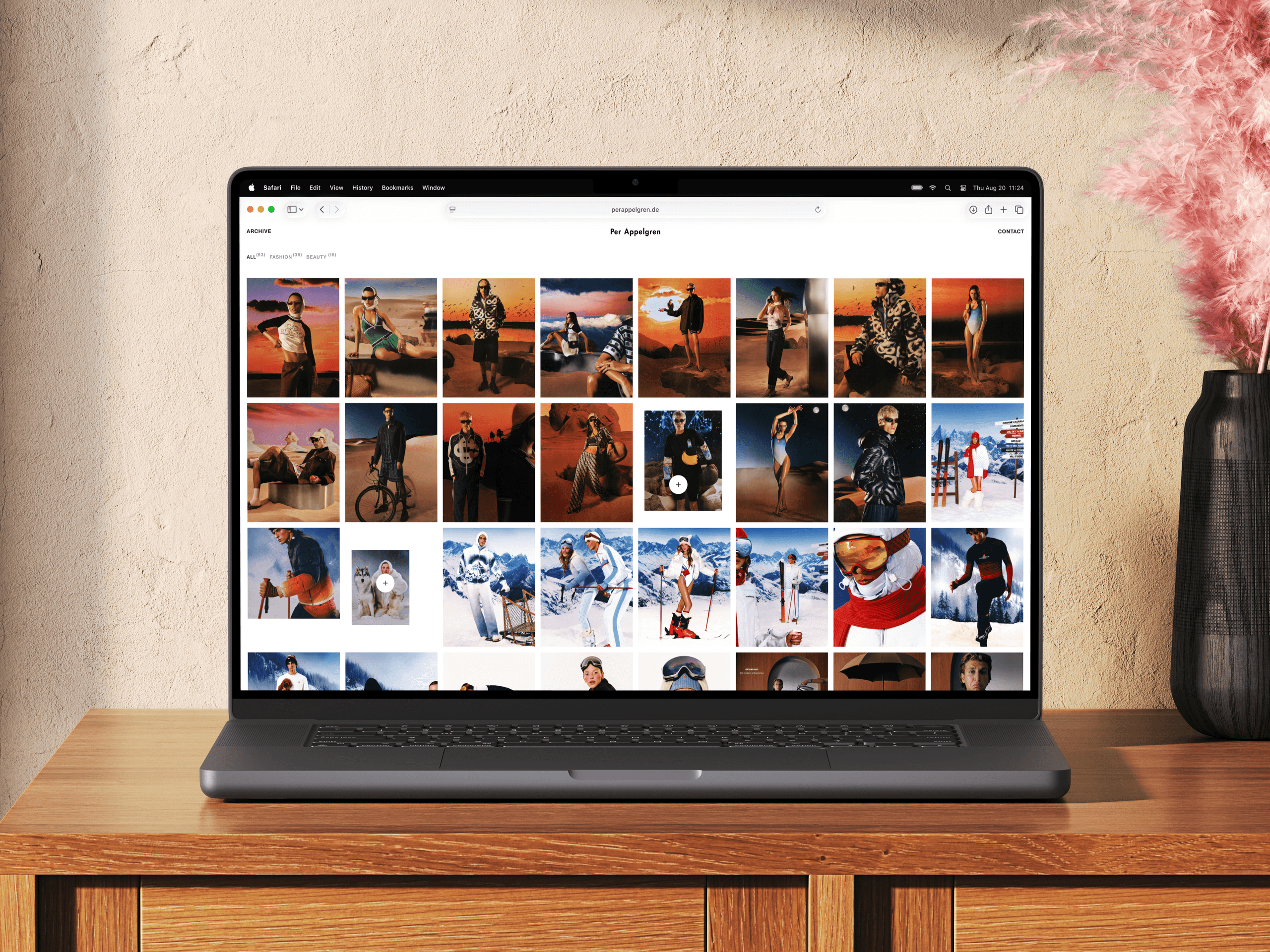 Laptop showing the portfolio archive in grid view, with fashion shots from desert and ski campaigns arranged in even rows.