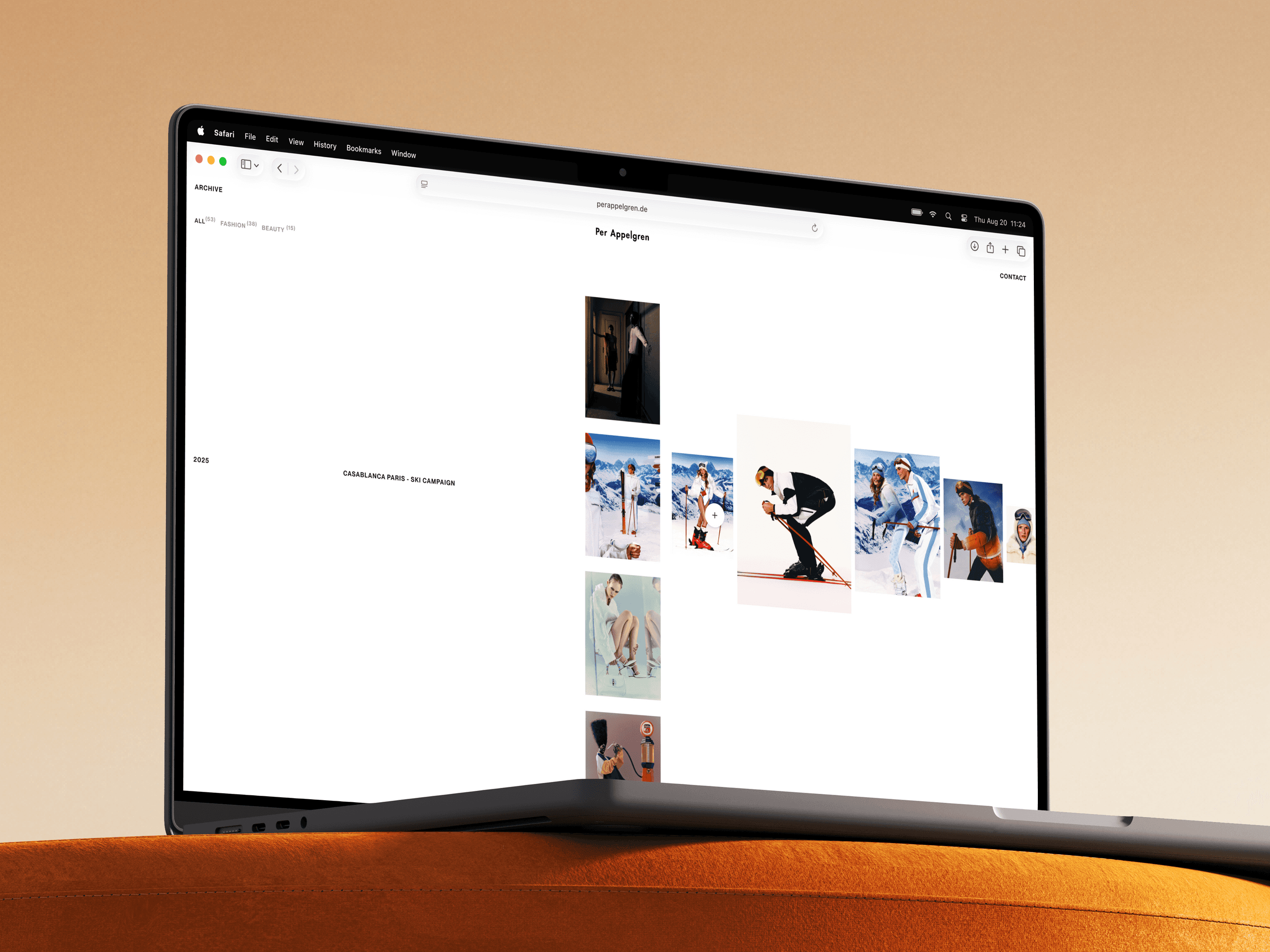 Low-angle view of a laptop on an orange sofa showing the archive, where the Casablanca Paris ski campaign opens into a sideways row of photos.